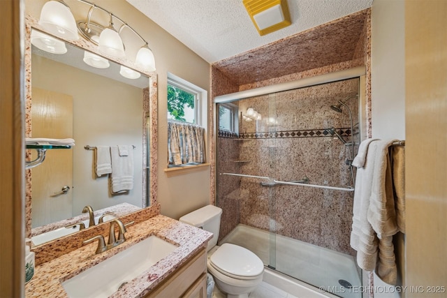 full bathroom with vanity, a shower stall, toilet, and a textured ceiling