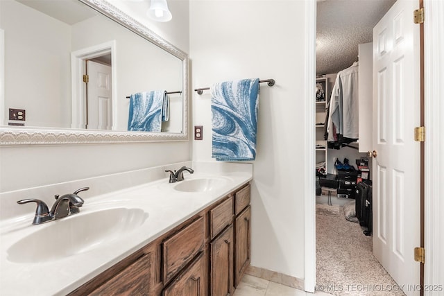 full bath featuring double vanity, a sink, a textured ceiling, and a spacious closet