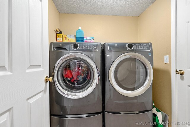 washroom featuring separate washer and dryer, laundry area, and a textured ceiling