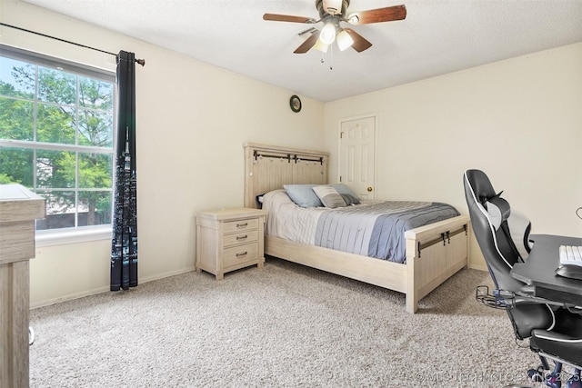 carpeted bedroom featuring a ceiling fan, baseboards, and multiple windows