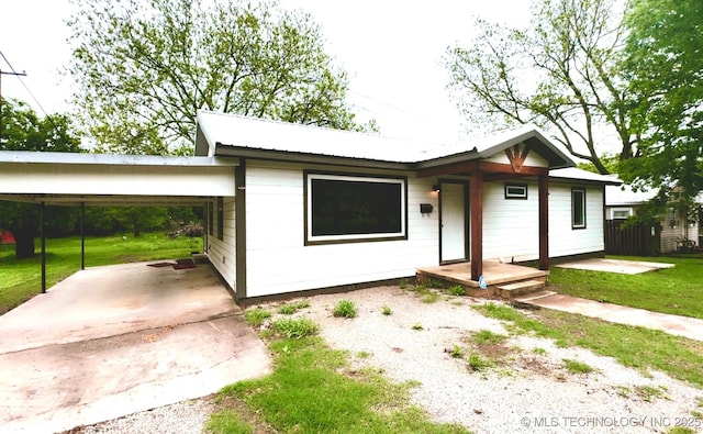 ranch-style house featuring driveway, metal roof, a front lawn, and a carport