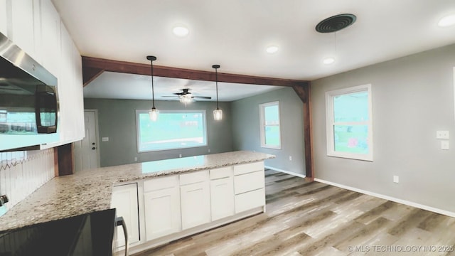 kitchen featuring ceiling fan, light stone countertops, stainless steel microwave, a peninsula, and white cabinetry