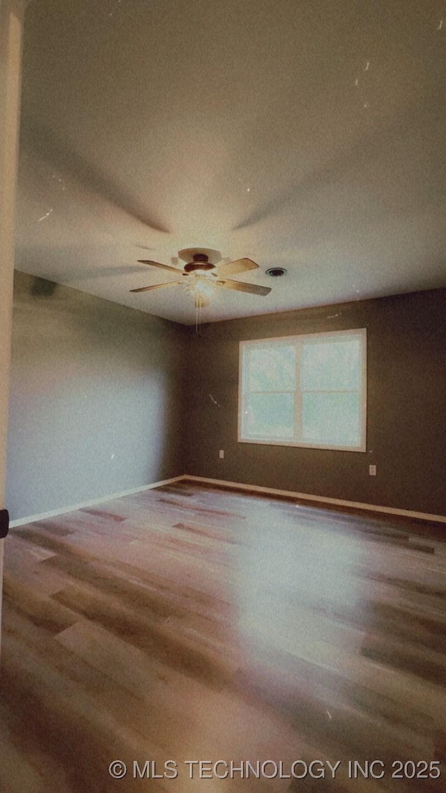 spare room featuring baseboards, a ceiling fan, and wood finished floors