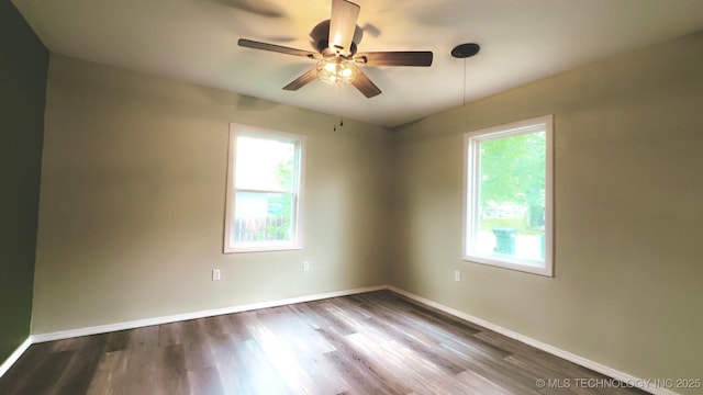 spare room with ceiling fan, a wealth of natural light, and wood finished floors
