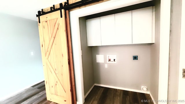 washroom featuring cabinet space, dark wood-style flooring, a barn door, hookup for a washing machine, and hookup for an electric dryer