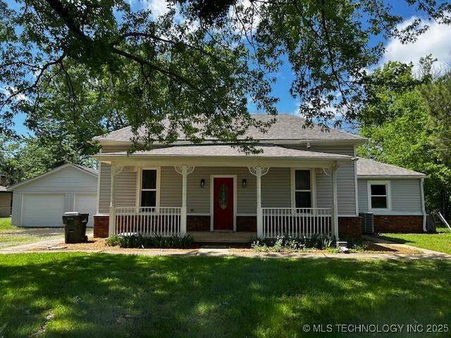 bungalow-style house featuring roof with shingles, a front lawn, brick siding, a detached garage, and covered porch