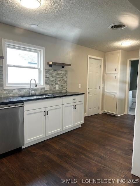 kitchen with dark wood-style flooring, a textured ceiling, dark countertops, and dishwasher