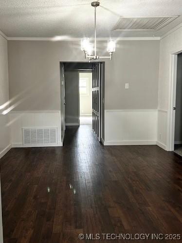 unfurnished dining area with dark wood-style flooring, visible vents, baseboards, a chandelier, and ornamental molding