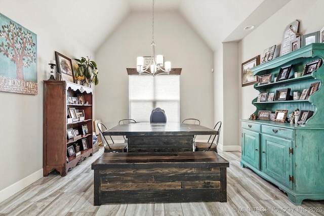 dining room featuring baseboards, light wood finished floors, lofted ceiling, and a chandelier