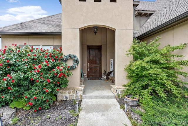 property entrance with roof with shingles and stucco siding
