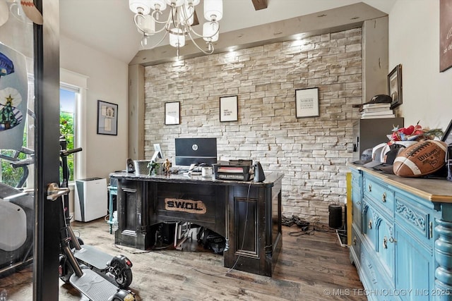 office space with an inviting chandelier, lofted ceiling, and wood finished floors