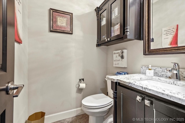 bathroom with vanity, baseboards, tile patterned floors, and toilet