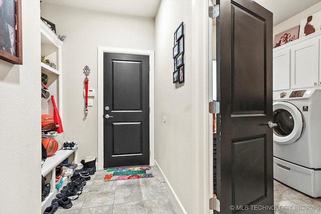 washroom with cabinet space, baseboards, and washer / dryer