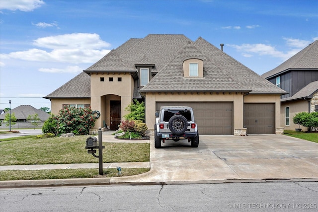 french provincial home featuring a shingled roof, a garage, stucco siding, a front yard, and driveway