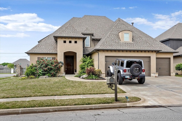 french country home with a shingled roof, an attached garage, a front lawn, stucco siding, and concrete driveway