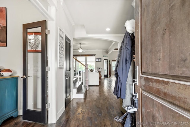 foyer entrance with crown molding, arched walkways, a ceiling fan, and dark wood finished floors