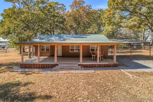 rear view of property featuring covered porch, log veneer siding, and metal roof