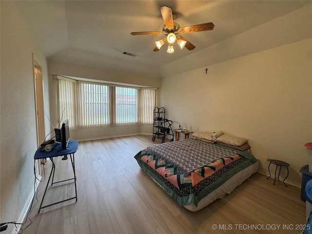 bedroom with a ceiling fan, visible vents, wood finished floors, baseboards, and lofted ceiling