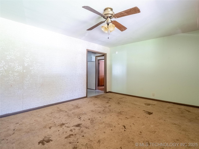carpeted spare room with baseboards and a ceiling fan