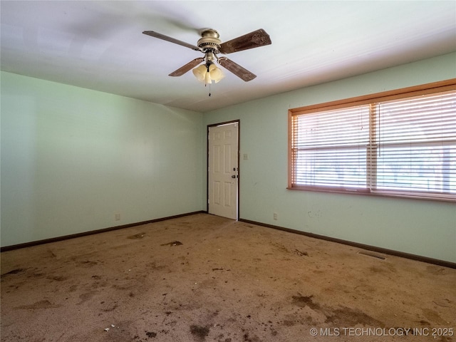 carpeted empty room with ceiling fan, visible vents, and baseboards