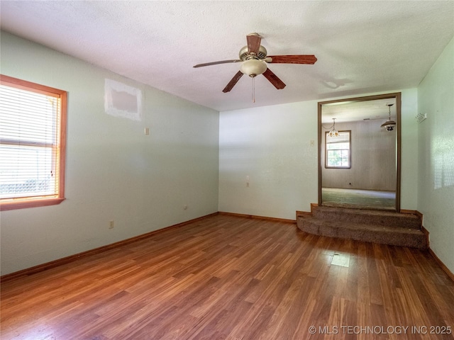 spare room featuring baseboards, ceiling fan, and wood finished floors
