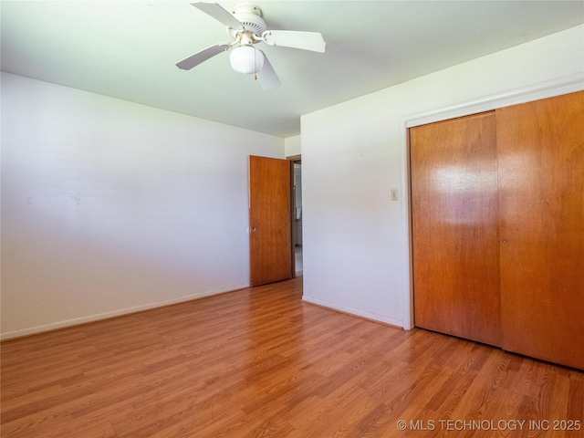 unfurnished bedroom featuring baseboards, ceiling fan, a closet, and wood finished floors