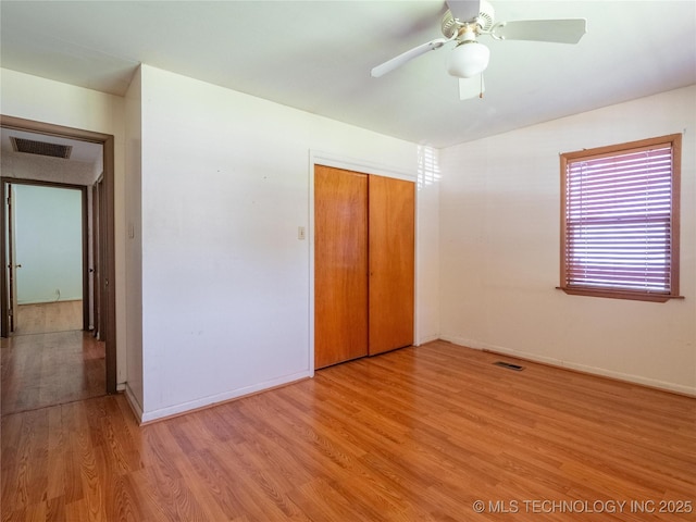unfurnished bedroom featuring visible vents, light wood finished floors, baseboards, and a closet
