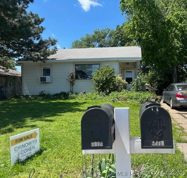 view of front of house with fence, a front yard, and cooling unit
