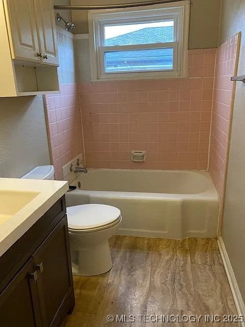 bathroom with toilet,  shower combination, wood finished floors, and vanity
