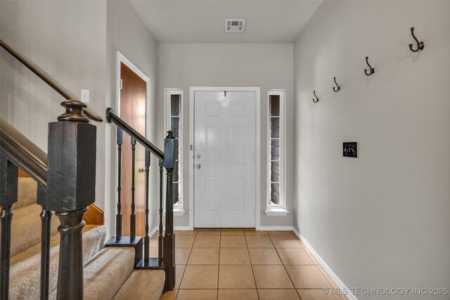 tiled foyer entrance with visible vents, stairs, and baseboards