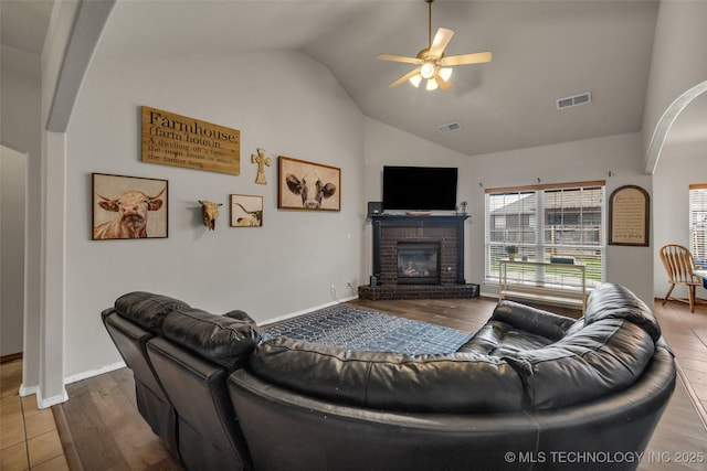 living room featuring a brick fireplace, a ceiling fan, visible vents, and lofted ceiling