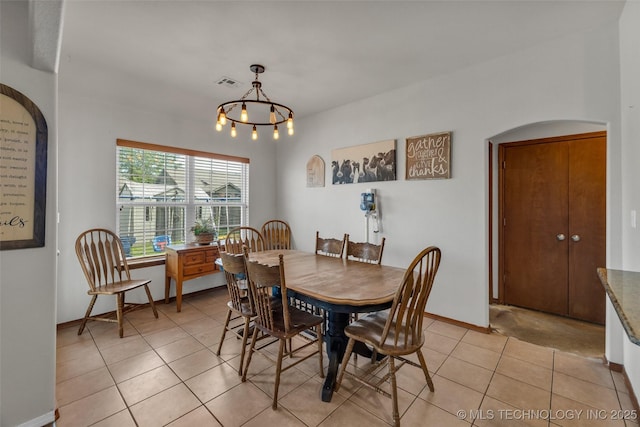 dining room with a notable chandelier, arched walkways, baseboards, light tile patterned floors, and visible vents