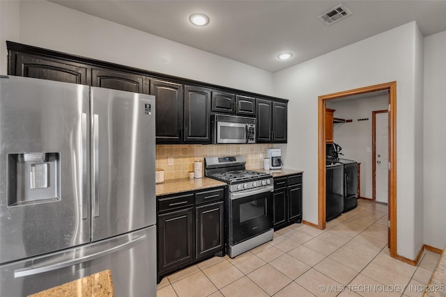 kitchen featuring visible vents, light tile patterned flooring, separate washer and dryer, backsplash, and stainless steel appliances