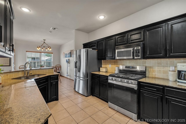 kitchen with dark cabinets, stainless steel appliances, and a sink