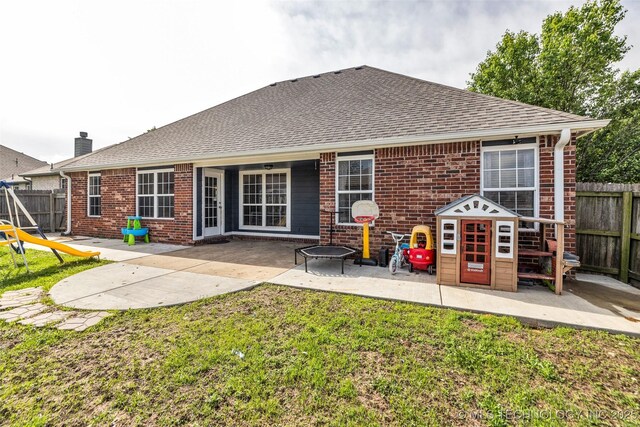 back of property with brick siding, a patio, fence, and a shingled roof