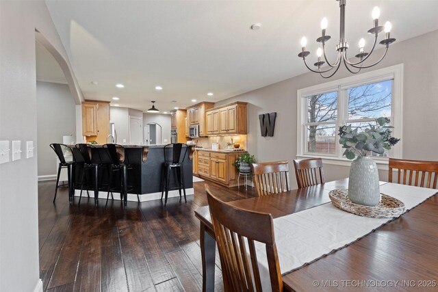 dining room with dark wood-style flooring, an inviting chandelier, arched walkways, recessed lighting, and baseboards