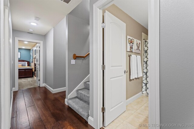 hallway featuring baseboards, stairs, and hardwood / wood-style floors
