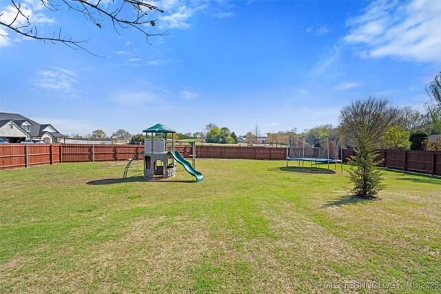 view of yard with a fenced backyard, a trampoline, and a playground