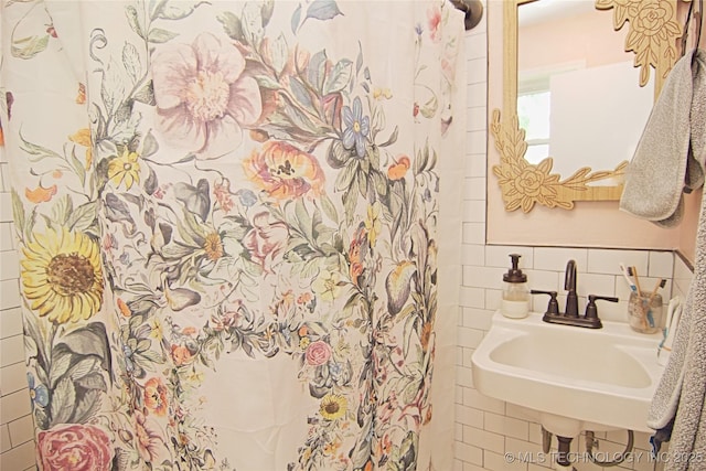 bathroom with a sink, tile walls, and tasteful backsplash
