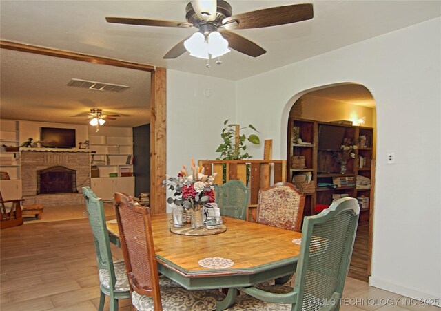 74703 S 320th Rd, Wagoner, OK 74467 - dining area with arched walkways, a ceiling fan, a brick fireplace, and visible vents