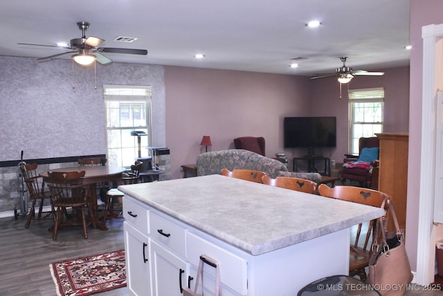 kitchen with ceiling fan, a center island, light countertops, white cabinets, and dark wood-style floors