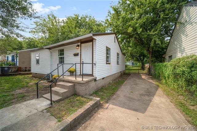view of front facade with crawl space, fence, and concrete driveway