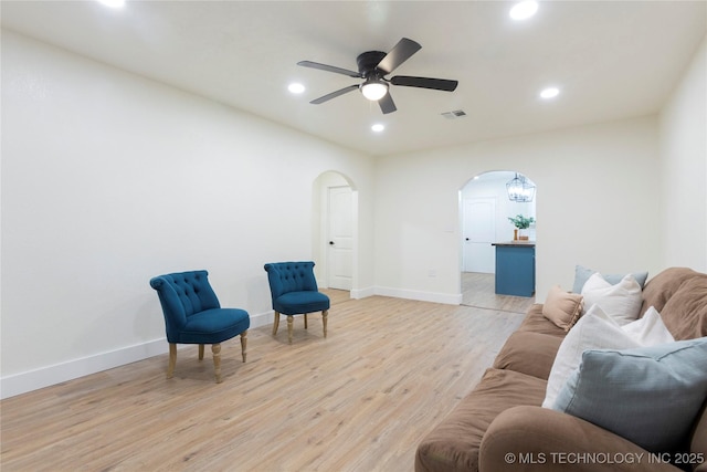 living area featuring arched walkways, visible vents, light wood-style flooring, and recessed lighting