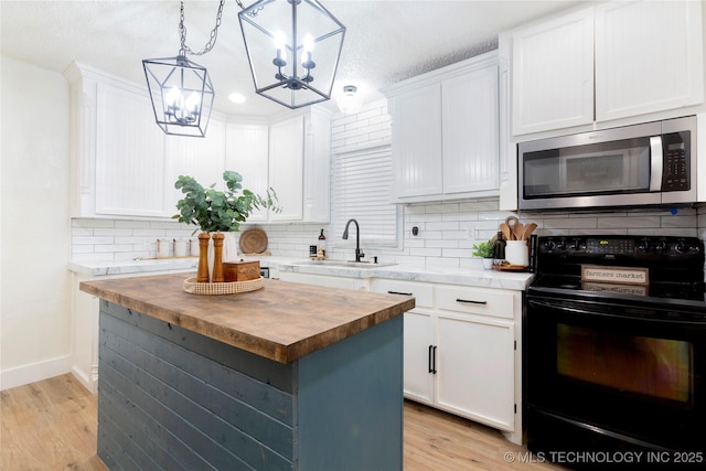 kitchen with black range with electric cooktop, stainless steel microwave, white cabinets, a sink, and wood counters