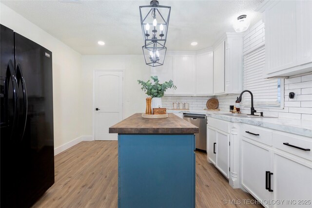 kitchen with a kitchen island, tasteful backsplash, dishwasher, black fridge, and butcher block countertops