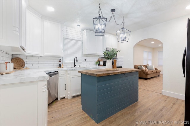 kitchen with a sink, arched walkways, decorative backsplash, and dishwasher