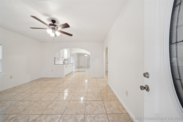 unfurnished room featuring arched walkways, ceiling fan, and a sink