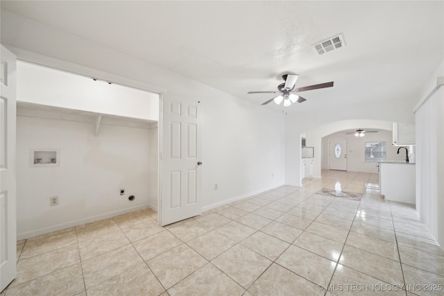 unfurnished room featuring visible vents, a sink, ceiling fan, arched walkways, and light tile patterned floors
