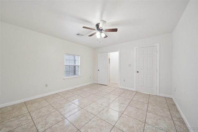 empty room featuring baseboards, ceiling fan, visible vents, and light tile patterned floors