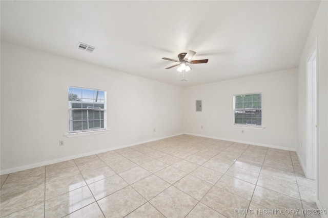 empty room featuring visible vents, ceiling fan, light tile patterned flooring, and a healthy amount of sunlight